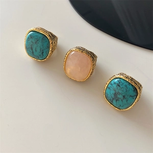Detail of three vintage rings featuring large pink crystal and turquoise on gold bands
