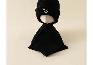 Detail of black knitted baby hat and scarf set with white embroidered heart patterns