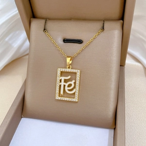 Close-up of gold hollow square necklace pendant with pavé crystals and Fe engraving