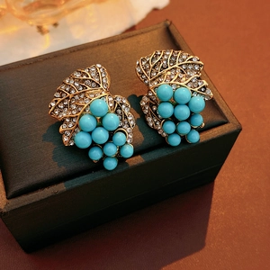 Macro shot of vintage grape leaf earrings with turquoise beads and inlaid crystals