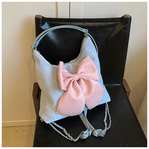 Detail of light blue crossbody bag featuring a large pink bow on a black chair