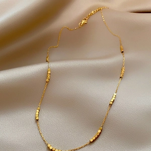 Vintage adjustable gold beaded geometric necklace on champagne silk fabric background