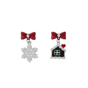 Detail of festive asymmetric earrings with red bow, white snowflake, and gingerbread house