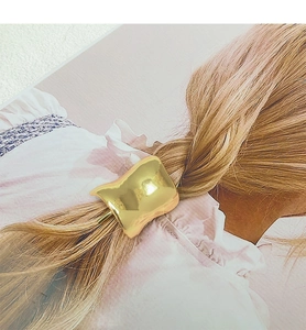 Detailed view of polished golden irregular alloy hair clip with smooth curved texture