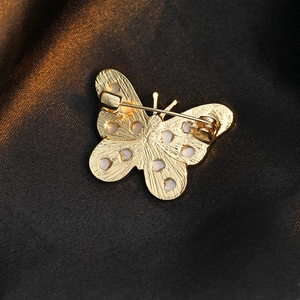 Elegant gold butterfly brooch with secure pin back on silk fabric background