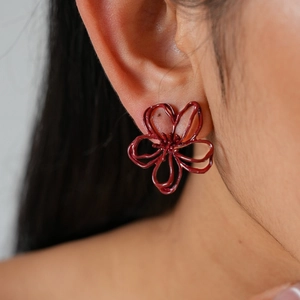Gros plan d'élégantes boucles d'oreilles fleurs bordeaux portées sur l'oreille d'un mannequin