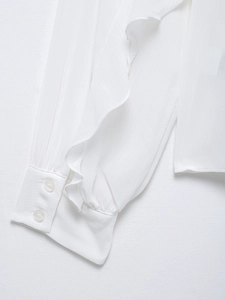 Close-up of white chiffon blouse sleeve with ruffle trim and elegant double-button cuff detail