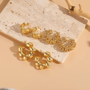 Macro view of C-shape twisted gold earrings with zircon stones and geometric spiral details