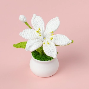 Handmade crochet white lily flower in ceramic pot on pink background