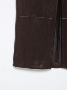Détail de la jupe midi en cuir marron foncé avec coutures texturées et fente élégante