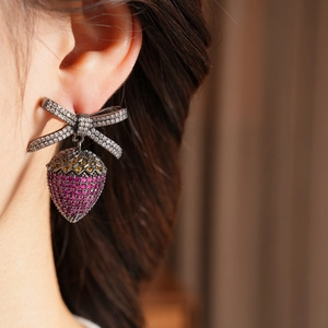 Close-up of strawberry crystal earrings with zircon bow on model for a vintage luxury look