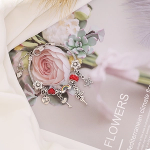 DIY silver charm bracelet with red hearts, rainbow and fairy pendants on silk fabric