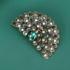 Detailed view of the peacock brooch featuring green rhinestones and a teardrop gem