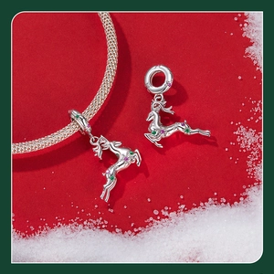 Macro shot of silver reindeer charm necklace with red and green stones on red background
