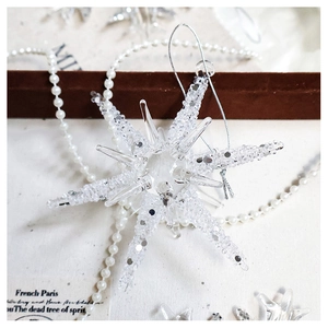 Macro shot of a transparent crystal snowflake ornament on a textured pearl background