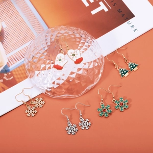 Five pairs of Christmas themed earrings featuring trees and snowflakes in festive colors