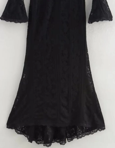 Detail of elegant black lace dress featuring long sleeves and scalloped wave hem edges
