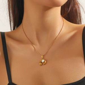 Minimalist gold-plated horseshoe necklace with pearl pendant worn on a model's neck
