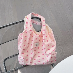 Detailed view of the pink heart pattern canvas tote bag hanging on a modern chair