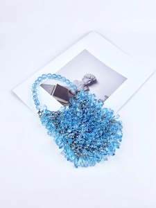Macro detail of hand-woven blue crystal beads on a stylish luxury evening handbag