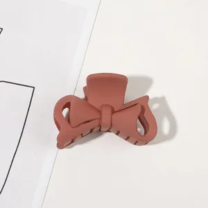 Detailed close-up of matte brick red bow hair claw clip with a sleek frosted resin finish