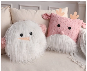 Detail of plush snowman and pink reindeer pillows on a soft sofa for cozy home decor