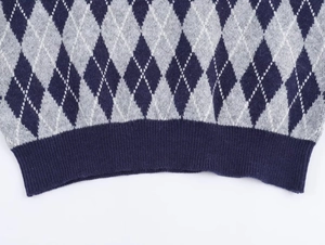 Close-up of the navy blue ribbed hem and classic Argyle knit pattern on the sweater