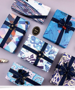Detail of luxury gift wrap sheets with blue geometric patterns and gold-edged satin ribbons