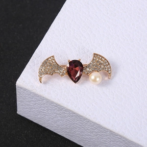 Macro shot of bat brooch with purple teardrop crystal and pearl detail on wings