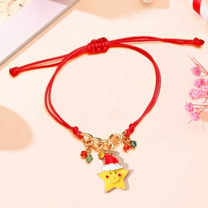 Detail of red braided holiday bracelet with a smiling gold star and Christmas hat charm