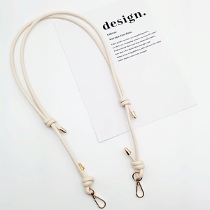 Detail of adjustable beige leather shoulder strap with gold metal spring buckles and hardware