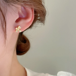 Gros plan d'une petite puce d'oreille fleur dorée au design de pétale minimaliste