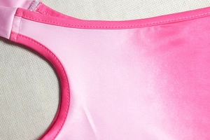 Dettaglio ravvicinato del tessuto elasticizzato rosa sfumato con cuciture di precisione