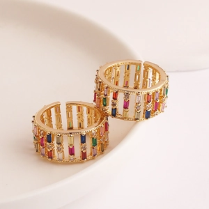 Macro shot of two gold rings with multi-colored baguette-cut zircons on a ceramic plate