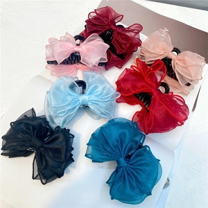 Elegant organza bow hair claws in seven assorted colors displayed on a white book