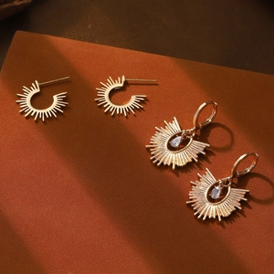 Détail de boucles d'oreilles soleil vintage dorées avec cristal goutte et motif de rayons