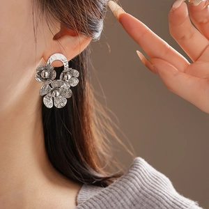 Close-up of model wearing silver wrinkled floral earrings with metallic petal texture