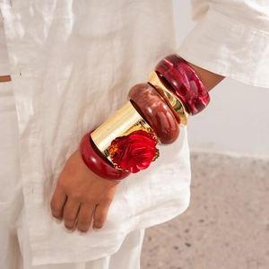 Close-up of bohemian resin bangles and gold metal cuff with a 3D red rose detail