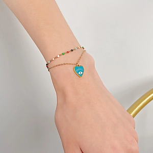 Detail of a double-layer gold titanium bracelet with colorful beads and blue heart evil eye