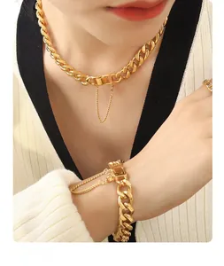 Close-up of gold chunky Cuban chain set with safety chain detail worn on a model