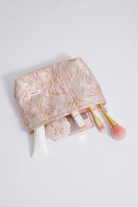 Detailed interior of jacquard floral makeup bag filled with cosmetics and skincare items