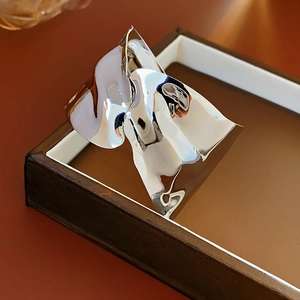 Dettaglio di un ampio bracciale rigido argento a onde su una scatola espositiva in legno