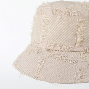 Beige woven bucket hat with distressed frayed edges and a minimalist retro sun protection style