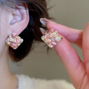 Detail of elegant gold-plated square studs with pink and yellow enamel floral patterns