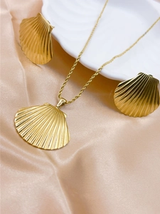 Detail of gold shell necklace and earrings set displayed on champagne satin and a shell tray