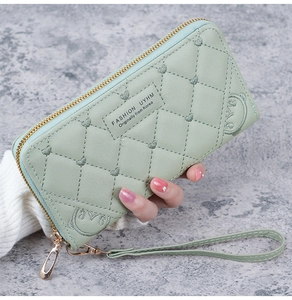 Detail of light green quilted long wallet with heart accents and gold zipper strap