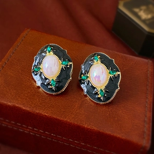Détail de boucle d'oreille vintage avec opale et gemmes vertes sur fond en cuir brun