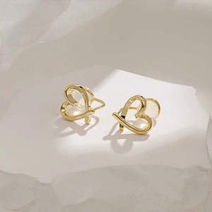 Detail of gold heart ear cuff featuring a cat-eye stone bead on white stone