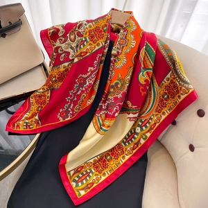 Detailed drape of colorful paisley silk scarf in red and gold over a black dress