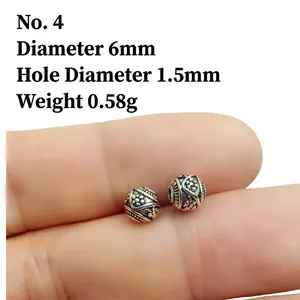 Close-up of 6mm Tibetan silver lantern bead with vintage floral relief for DIY jewelry